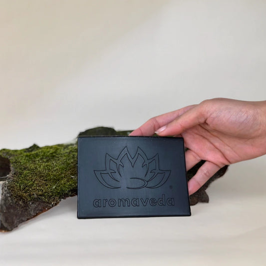 Schwarze Aromaveda Platte mit Lotus-Blumen und aromaveda Gravur gehalten von einer Hand