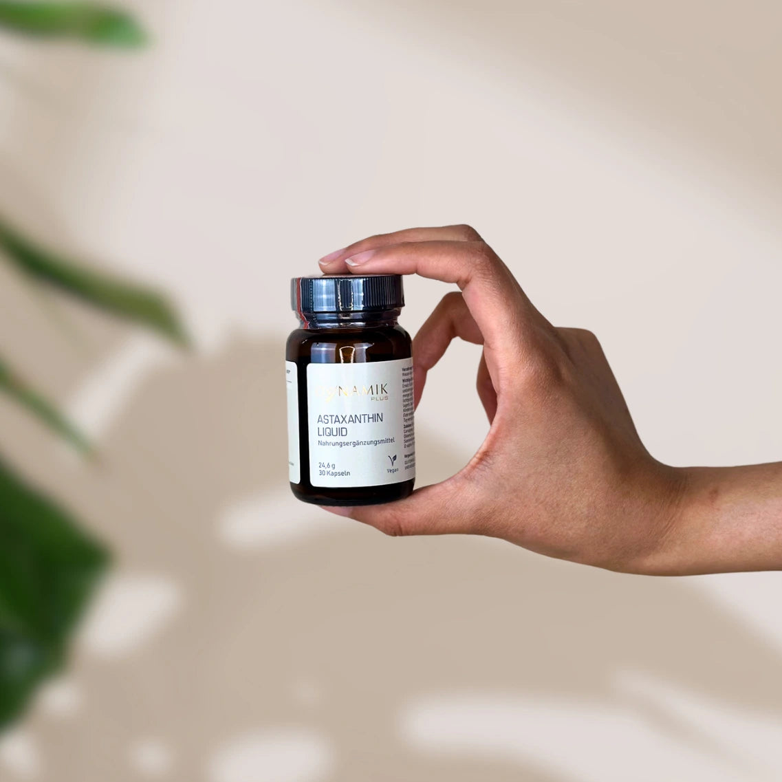 Brauner kleiner Glasbehälter mit DynamikPlus "Astaxanthin Liquid" Etikett und schwarzem Drehverschluss