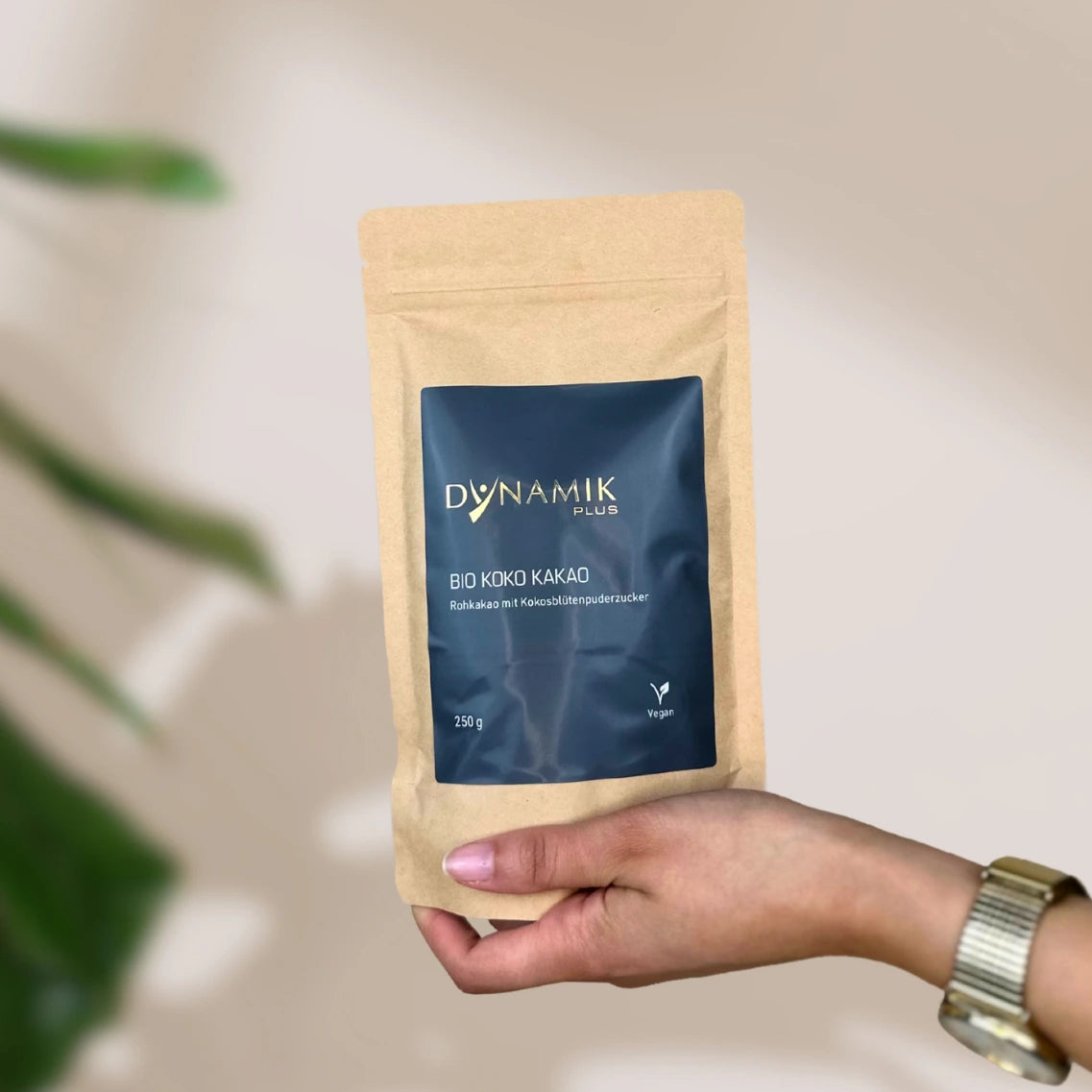 Beiger Kartonbeutel mit DynamikPlus "Bio Koko Kakao" Etikett gehalten in Hand