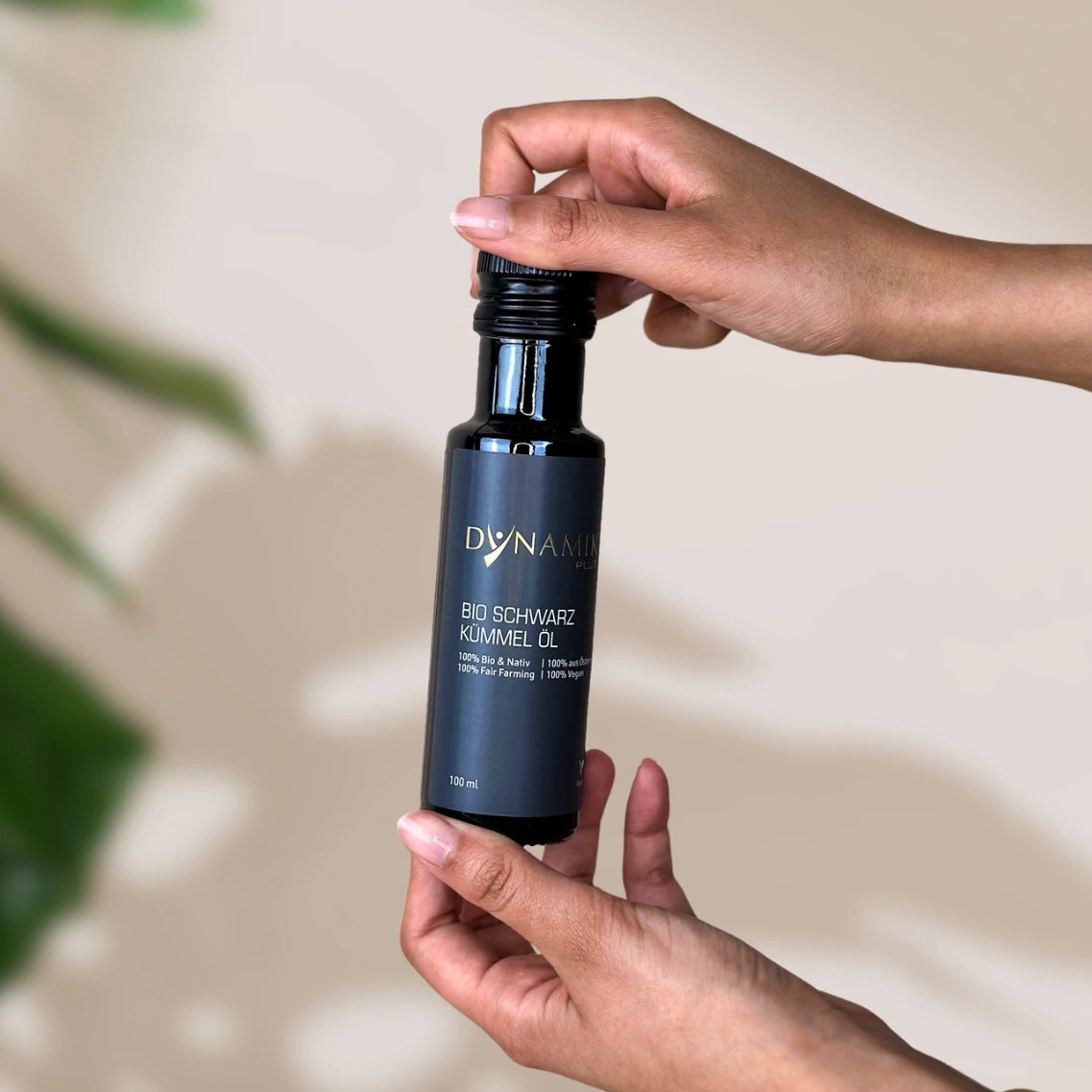 Kleine Ölflasche mit DynamikPlus "Bio Schwarzkümmelöl" Etikett in Hand gehalten