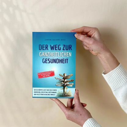 Hände halten das Buch "Der Weg zur ganzheitlichen Gesundheit"