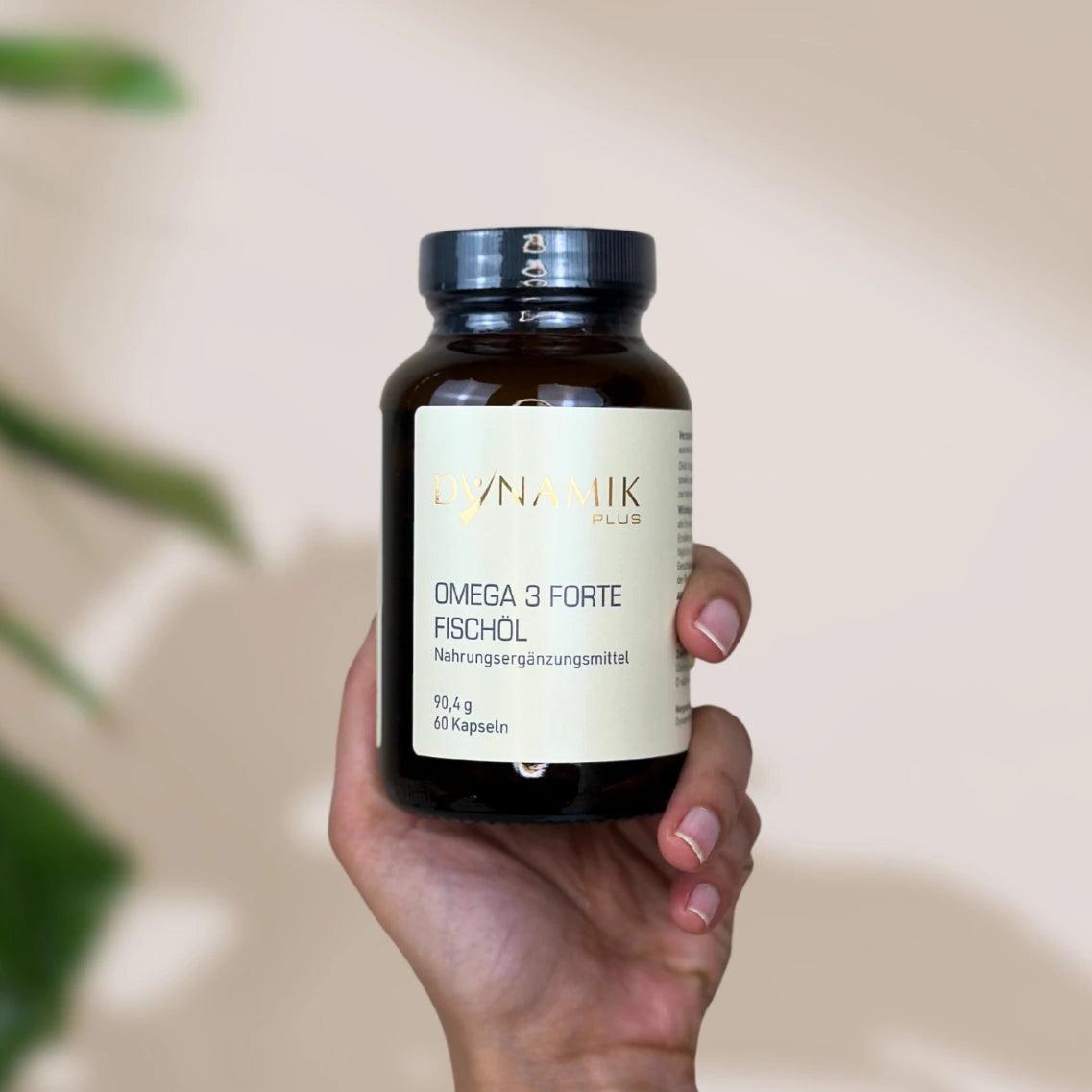Brauner Glasbehälter mit DynamikPlus "Omega 3 Forte Fischöl" Etikett und schwarzem Drehverschluss von einer Hand gehalten