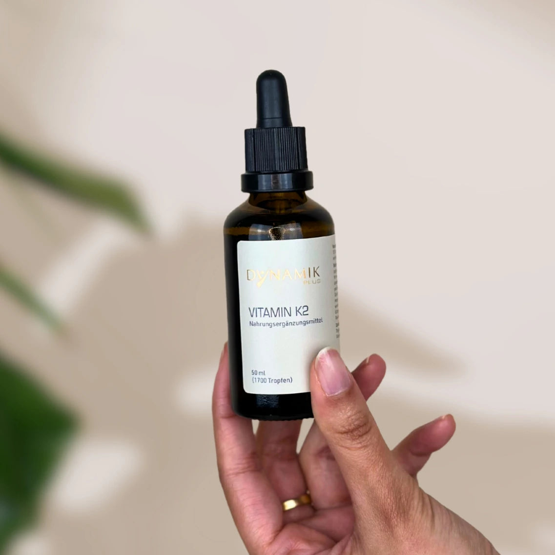 Braune Tröpfchenflasche mit DynamikPlus "Vitamin K2" Etikett auf der Flasche